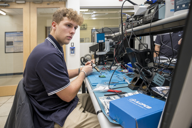 COE - ECE - Dental Device - 11.01.23 Bryce Carlson uses a soldering iron and other electronic testing tools at a work bench.