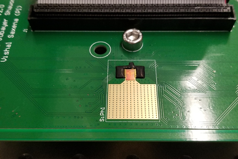 Small bronze-colored computer chip attached to a green board.